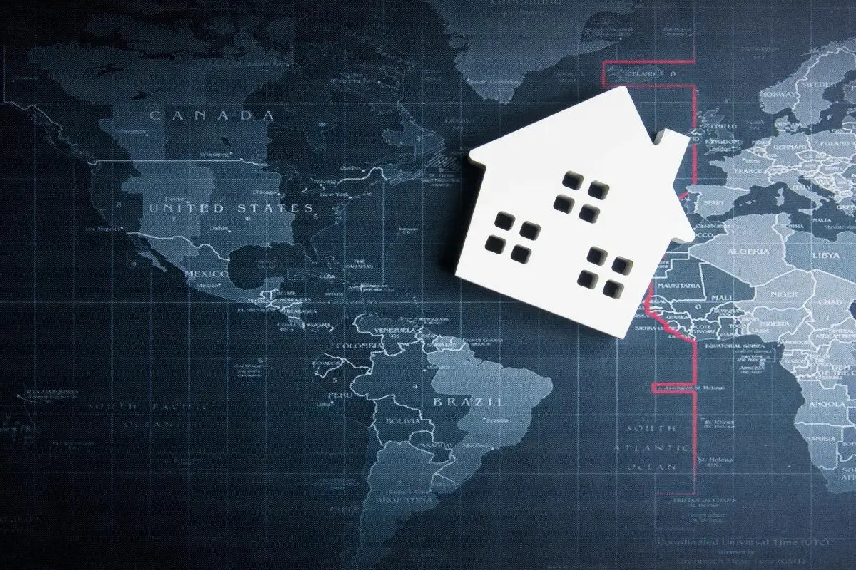 Global map background with a white house symbol representing overseas property investment from Canada