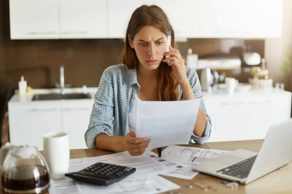 Woman reviewing bills and financial documents at home while calculating overseas expenses and managing cross-border payments.
