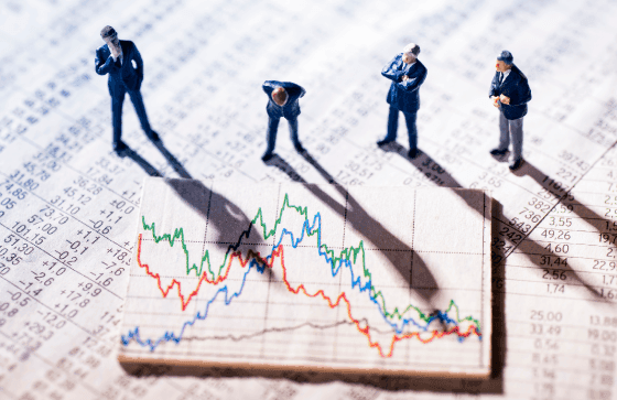 Miniature business figures examining a fluctuating currency exchange chart on a financial document—highlighting the complexities of managing foreign exchange (FX) risk in volatile currency markets.