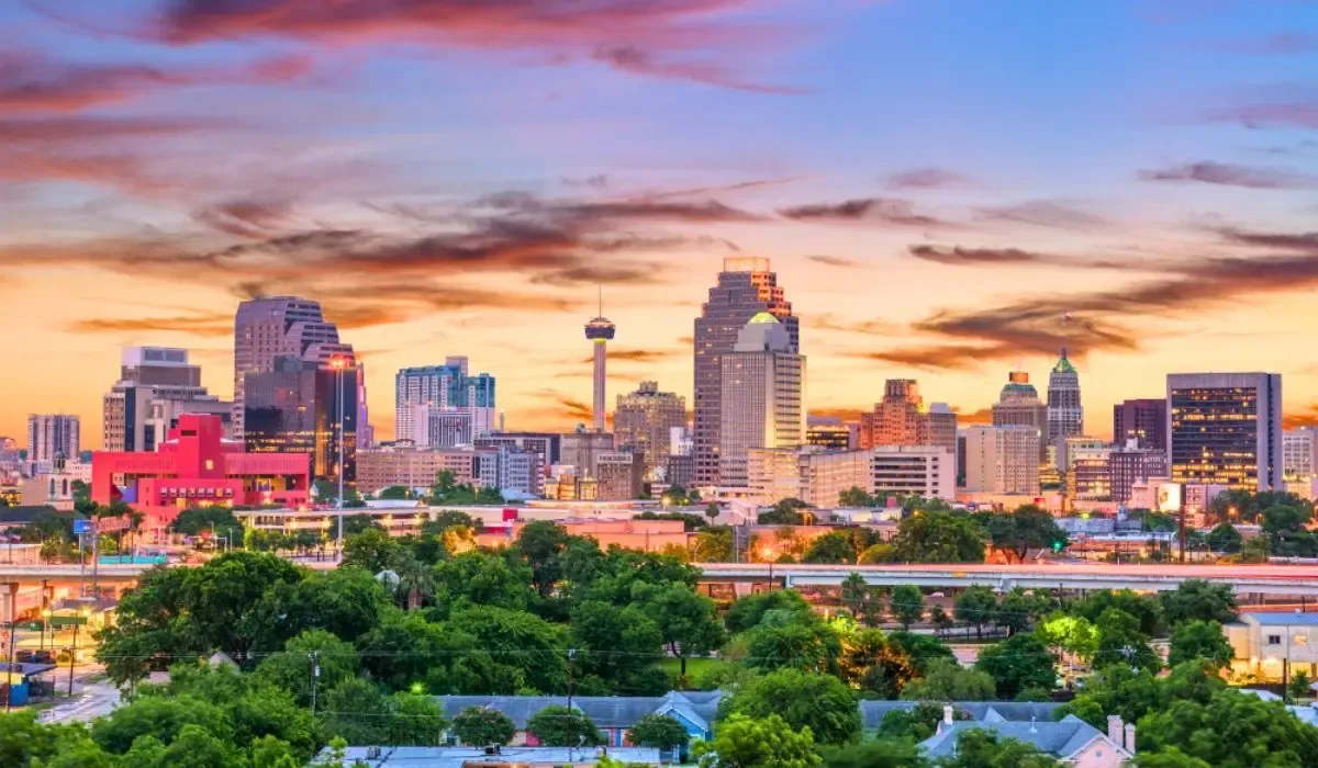 A view of San Antonio, Texas, highlighting the historic Alamo mission with surrounding greenery and a clear sky.