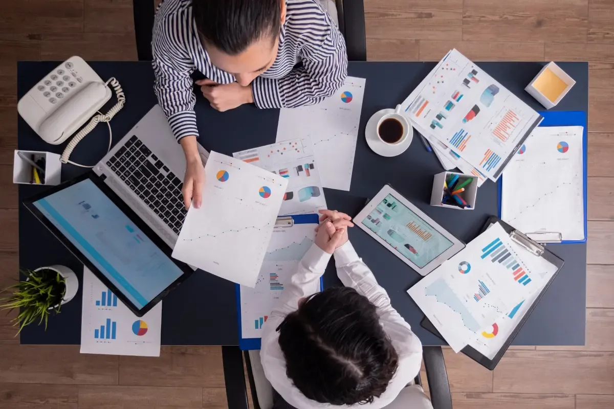 Business professionals reviewing financial charts and global payment data on a desk, analyzing exchange rate trends and international transaction performance