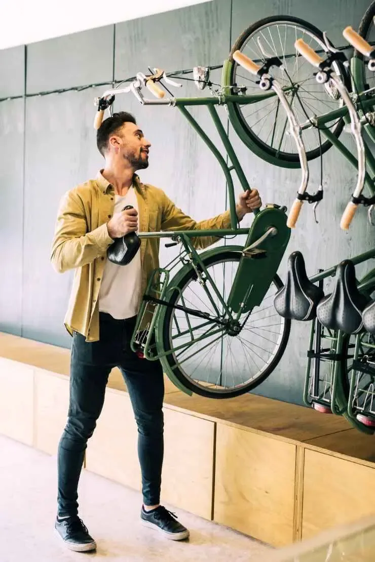 Man preparing a bicycle for display or repair in a retail or athletic environment, showcasing the sports sector.