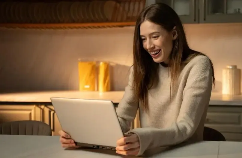 Happy woman using a laptop in a warmly lit room