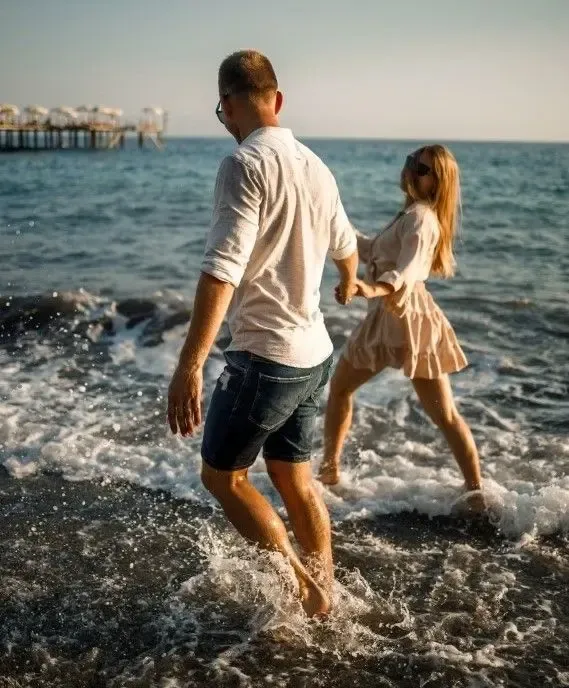 Couple walking along the beach shore, enjoying the waves and holding hands
