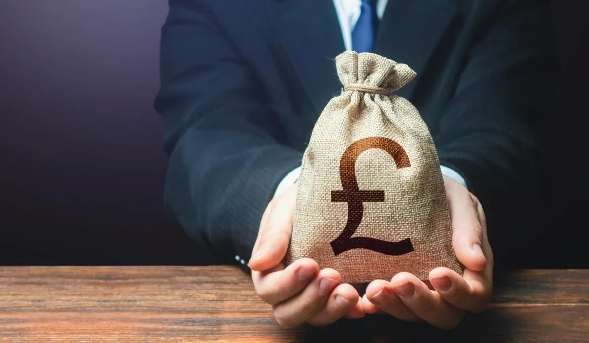 Business professional holding a money bag with British pound symbol, representing GBP transfers, currency exchange, savings, and international payments.