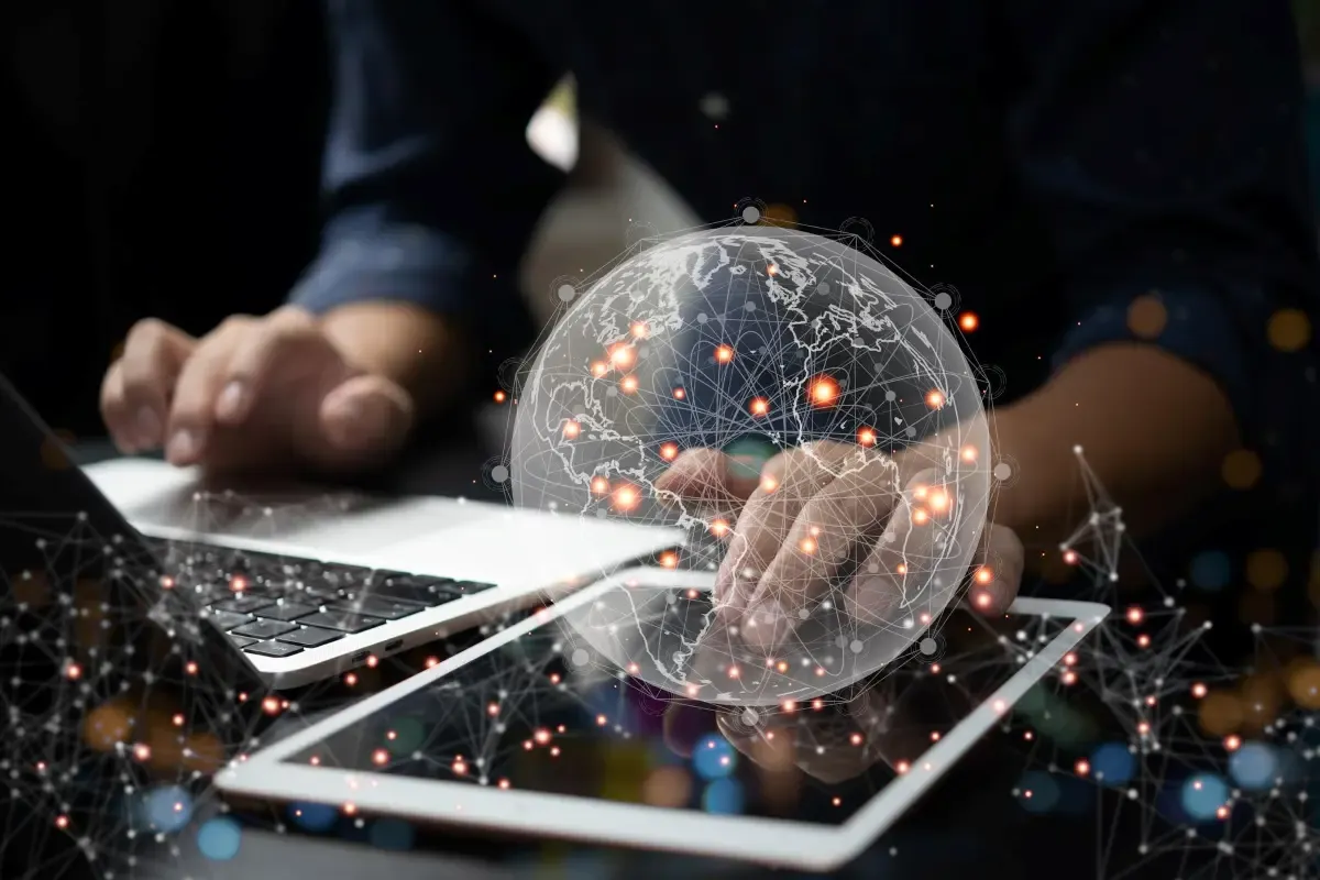 Digital global network overlay above laptop and tablet symbolizing international payments, currency exchange, and cross-border financial connectivity.