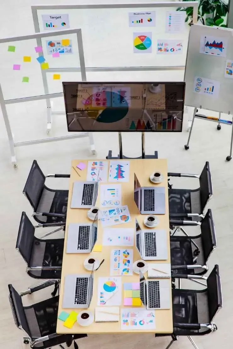 Office table with laptops, reports, and marketing charts, ready for a team brainstorming session.