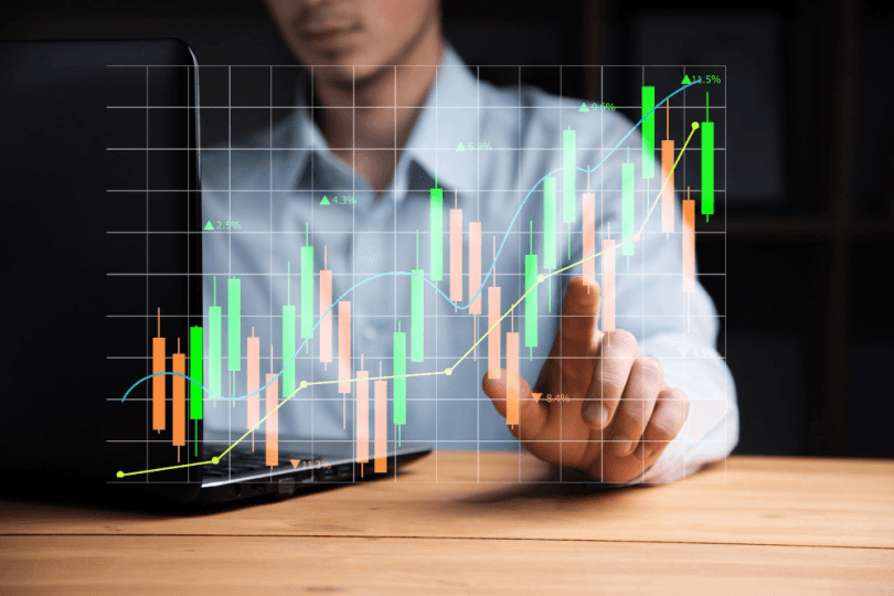 Business professional using a laptop with interactive financial growth chart overlay showing rising candlesticks and trend lines, representing FX strategy, market analysis, and profit growth.