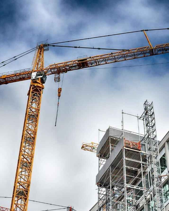 Tower cranes operating over a multi-story building under construction, highlighting the construction industry.