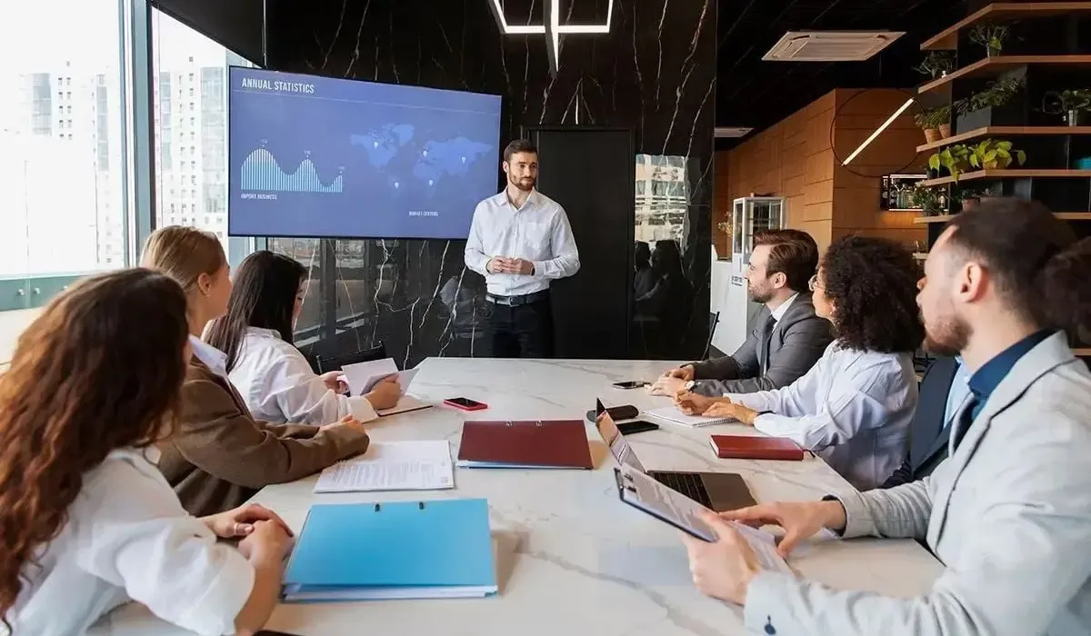 Business professional presenting annual statistics and global market data during a team meeting in a modern office boardroom.