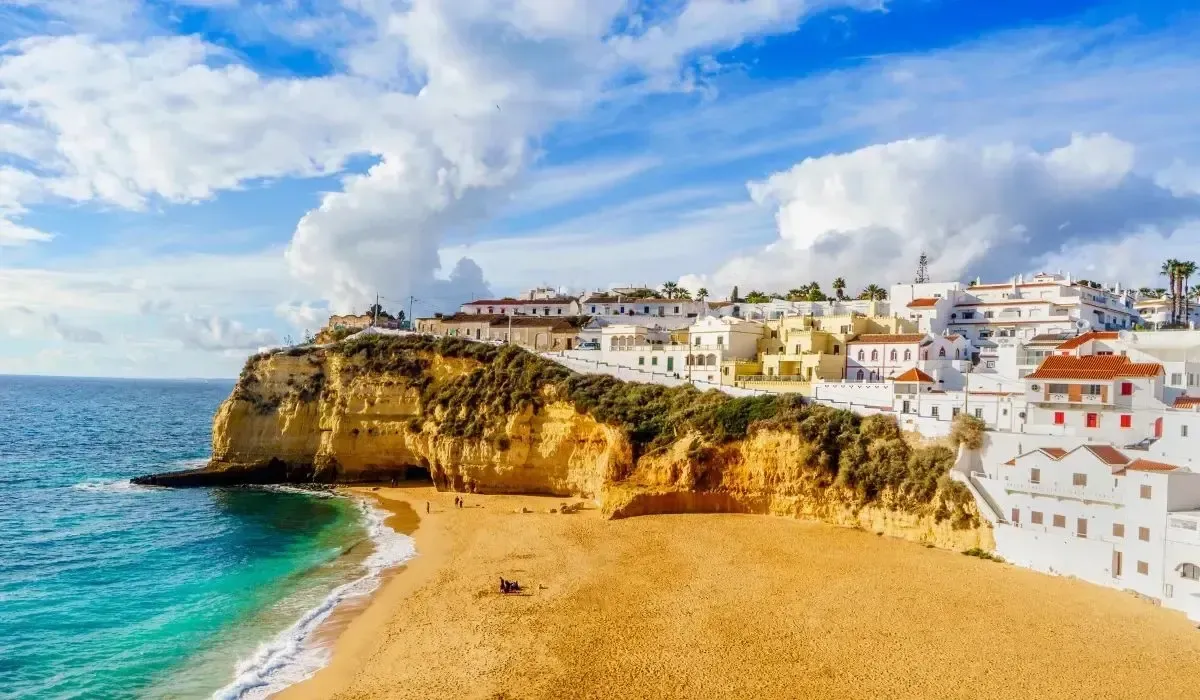 Golden cliffs and whitewashed houses overlooking a sandy beach in Algarve, Portugal, symbolizing buying overseas property and managing foreign exchange transfers from Canada to Portugal to pay for property purchases at competitive euro rates.