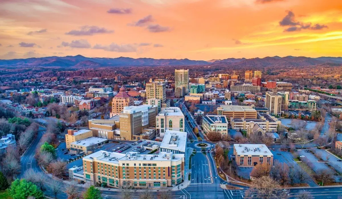 A panoramic image of Asheville, North Carolina, highlighting the city's historic architecture set against the backdrop of the Blue Ridge Mountains.