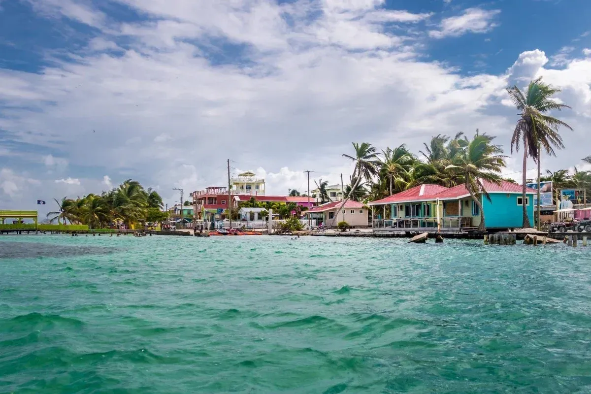 Turquoise water, palm trees and colourful waterfront homes along the coast in Belize.