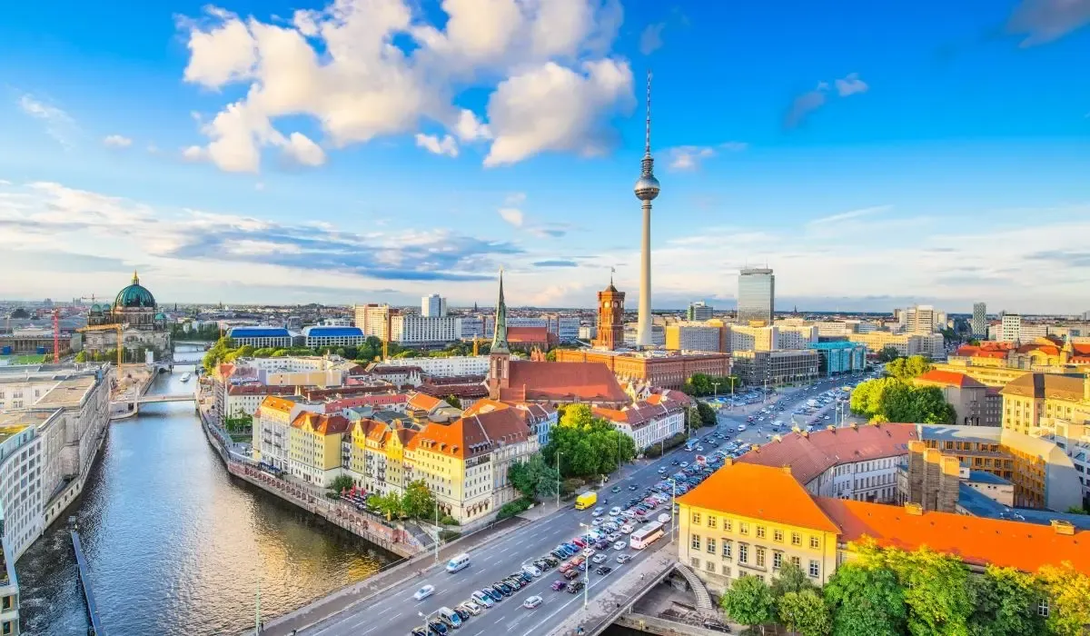 Vibrant aerial view of Berlin, Germany, showcasing the iconic TV Tower, Berlin Cathedral, and Spree River under a bright blue sky. Canadians buying property in Germany can benefit from favourable CAD to EUR exchange rates and low-cost transfers with MTFX.