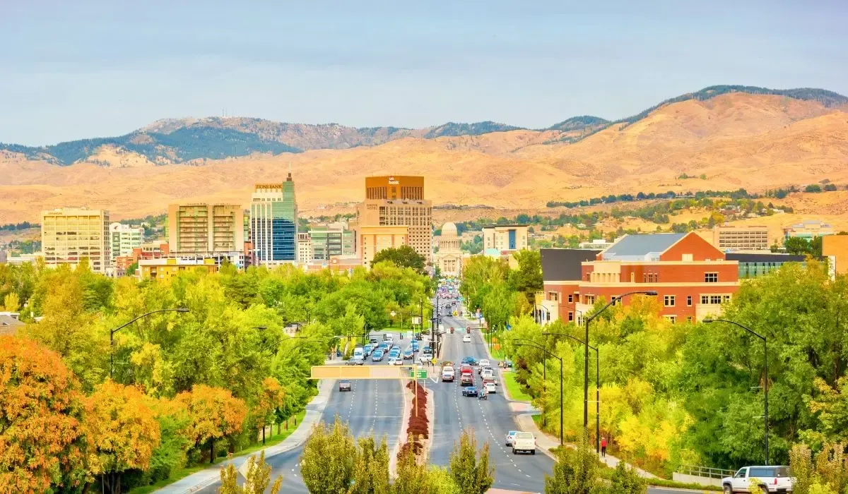 An aerial view of Boise, Idaho, displaying the city's skyline surrounded by lush greenery and the Boise River winding through.
