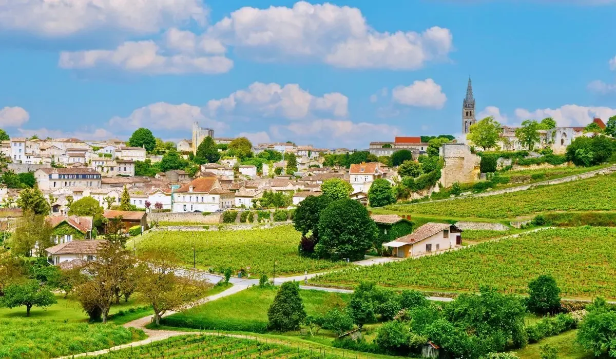 Expansive vineyards surrounding the charming village of Saint-Émilion near Bordeaux, France, with stone houses and a historic church tower. Canadians buying property in France can secure favorable CAD to EUR rates and affordable transfers through MTFX.