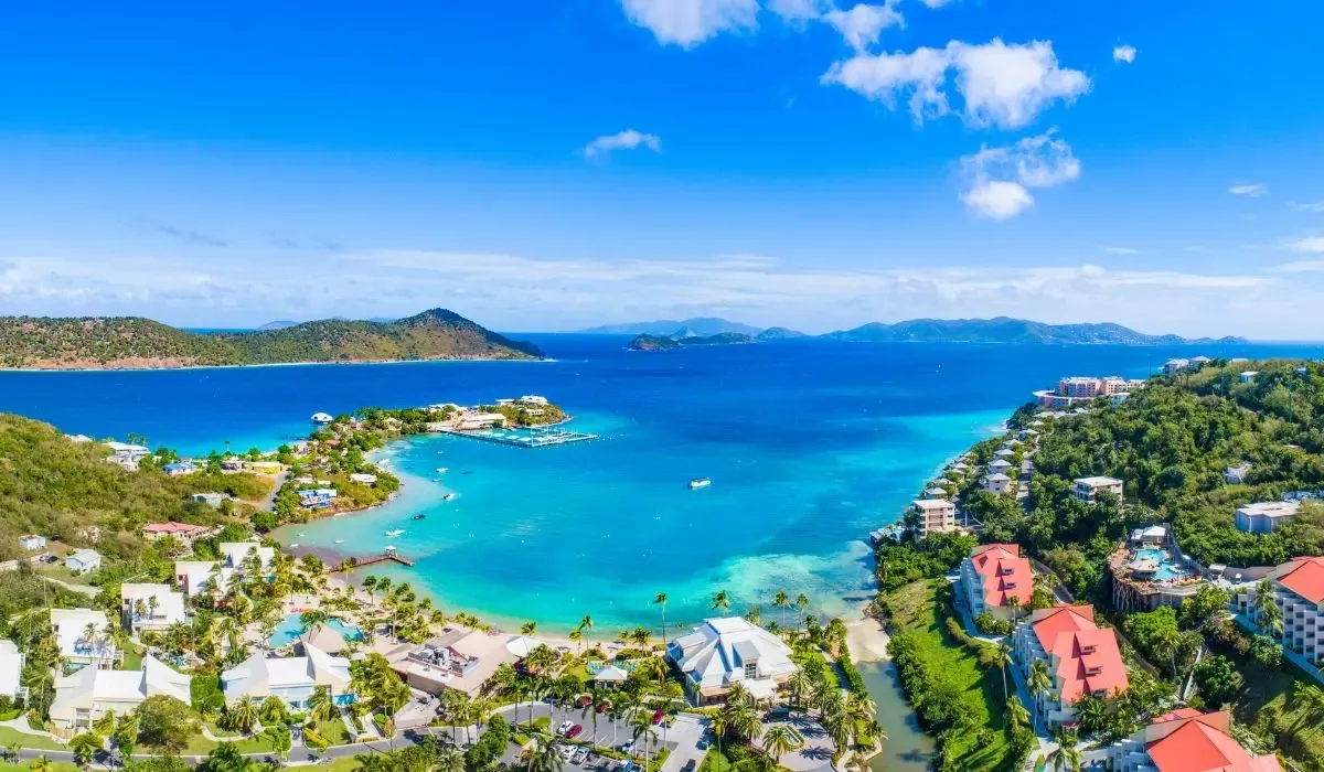 Aerial view of the Virgin Islands coastline with turquoise waters, villas, and lush green hills, showcasing an ideal location for property investment.