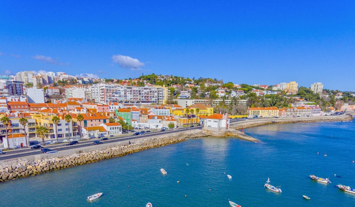 Seaside view of Cascais, Portugal with waterfront homes, palm trees, and vibrant coastal scenery