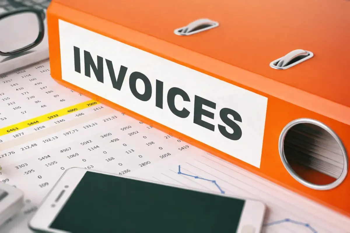 MTFX orange invoice folder on a desk with financial documents, calculator, and smartphone representing international invoice management and business payments