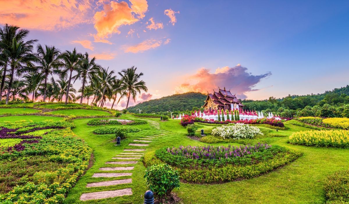 A panoramic view of Chiang Mai's historic Old City, featuring ancient temples, traditional Thai architecture, and surrounding mountains under a clear blue sky.