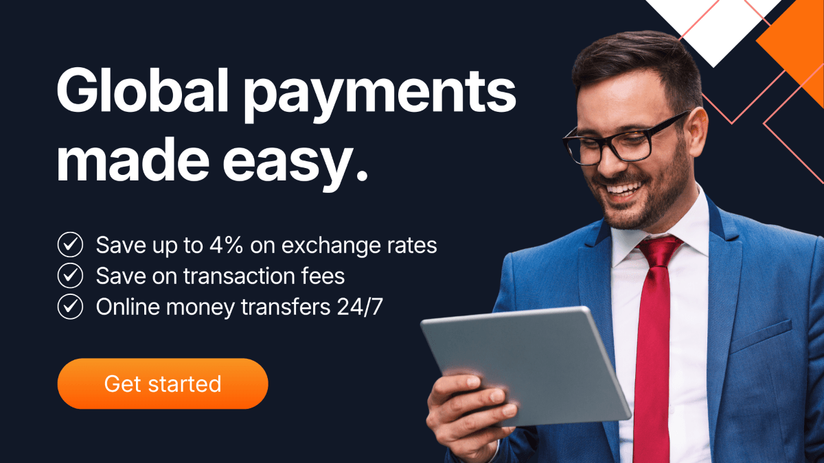 Smiling businessman in a blue suit using a tablet, with text promoting global payments made easy, highlighting savings on exchange rates, lower transaction fees, and 24/7 money transfers with a Get Started button.