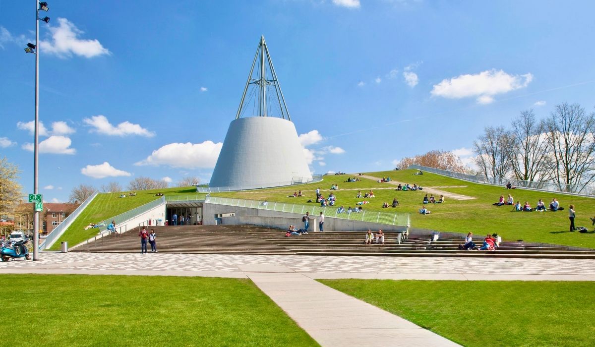 A modern architectural view of Delft's campus, highlighting innovative building designs and green spaces frequented by students.
