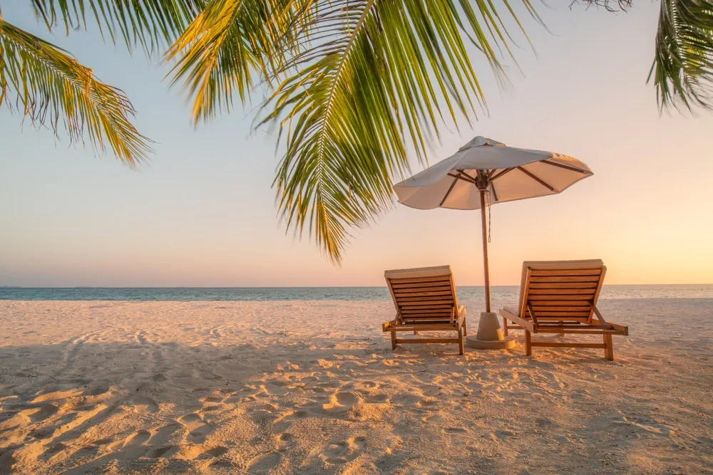 Peaceful beach in the Dominican Republic with palm trees, sun loungers, and calm ocean views at sunset.