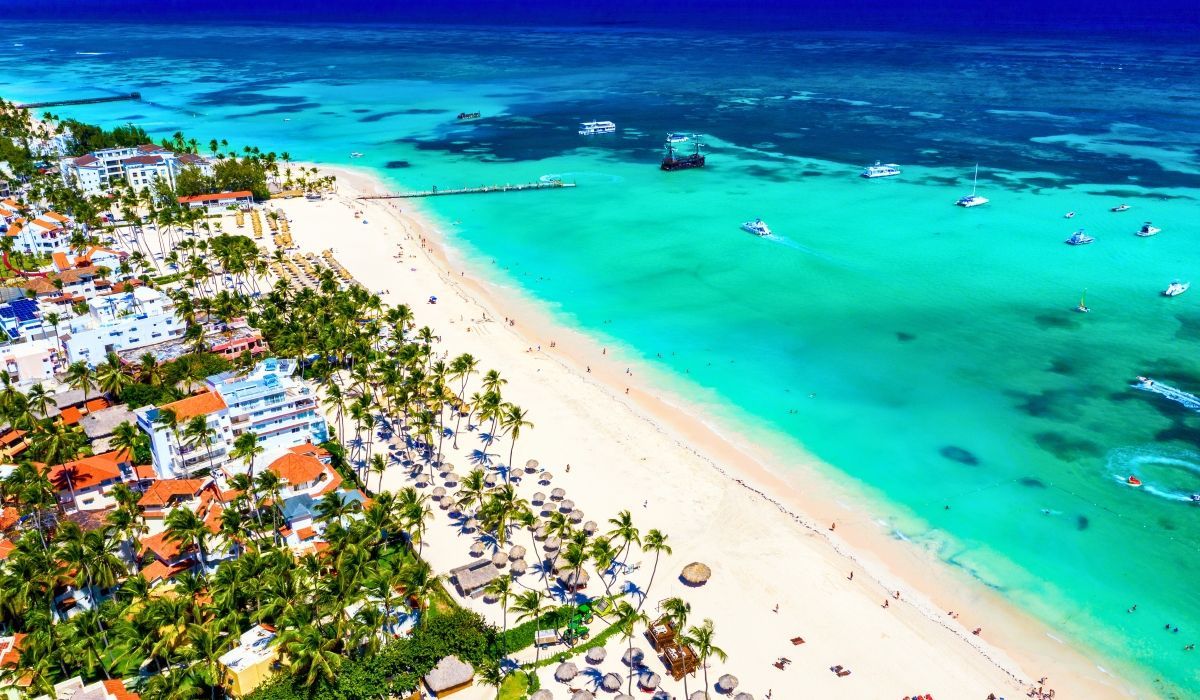 Punta Cana coastline in the Dominican Republic with white sandy beaches, turquoise water, and scattered palm trees.