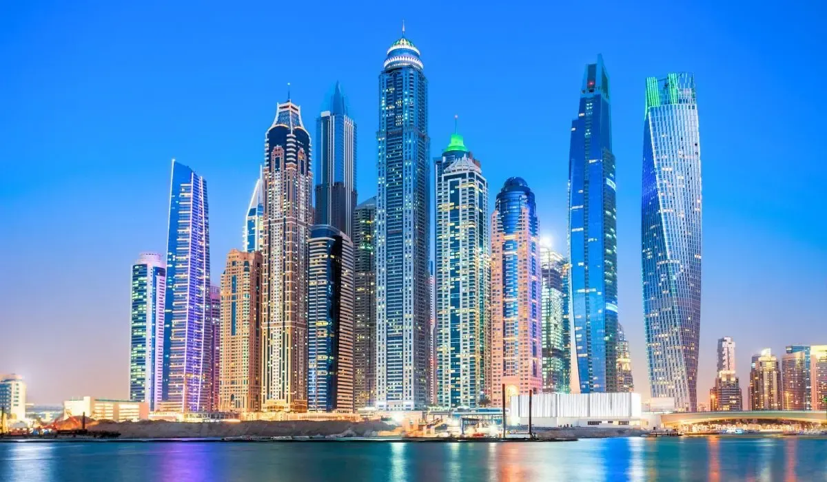 Skyline of Dubai, UAE illuminated at dusk, featuring soaring skyscrapers and futuristic architecture reflected over the marina waters. Canadians investing in property in Dubai can benefit from attractive CAD to AED exchange rates and secure global payments with MTFX.
