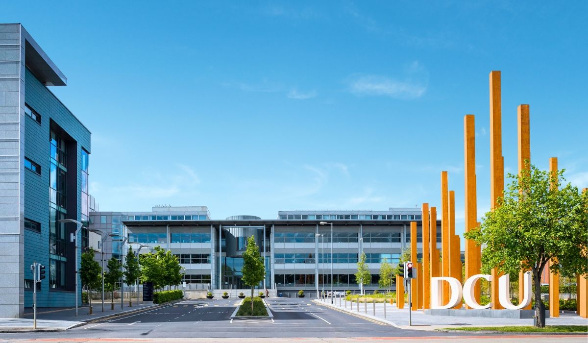 A vibrant scene of Dublin City University's campus, displaying modern academic buildings and students engaging in outdoor activities.​