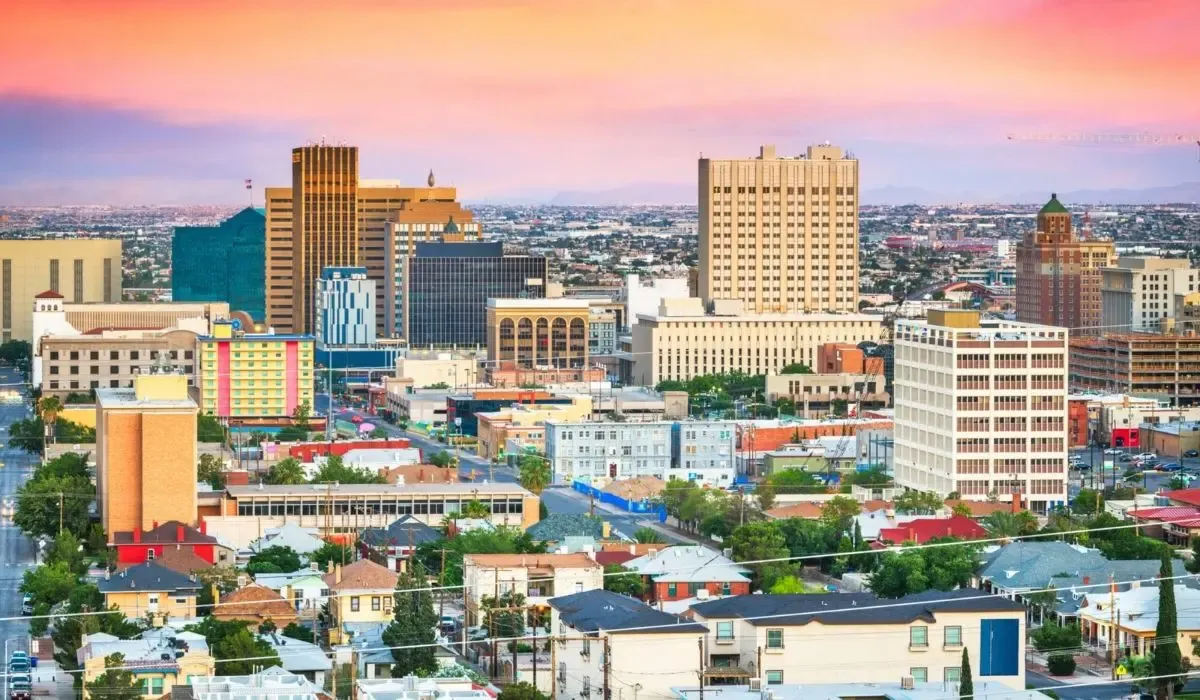 A landscape view of El Paso, Texas, highlighting the city's buildings set against the backdrop of the Franklin Mountains under a partly cloudy sky.