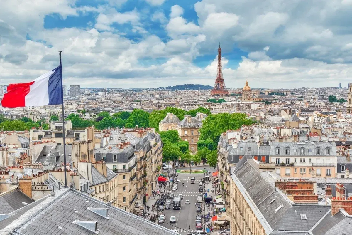 Paris skyline with the French flag, Eiffel Tower and city rooftops in the background.