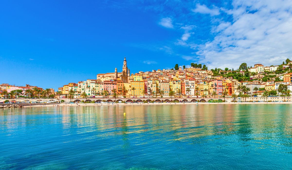 A vibrant coastal town on the French Riviera, showcasing pastel-colored buildings along a serene waterfront.
