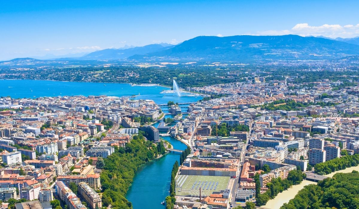 Aerial view of Geneva, Switzerland, showing the Jet d'Eau fountain and the cityscape nestled between rivers and Lake Geneva.
