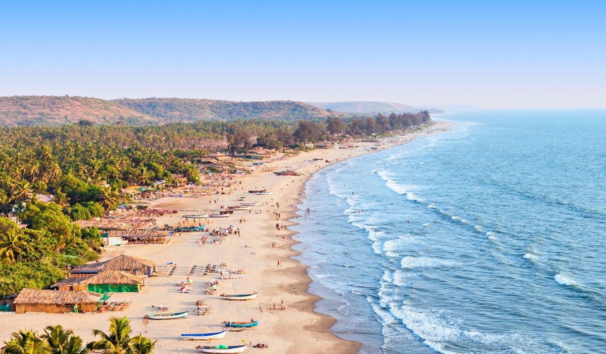Goa’s sandy beach lined with huts, sunbeds, and visitors enjoying the tropical coastline.