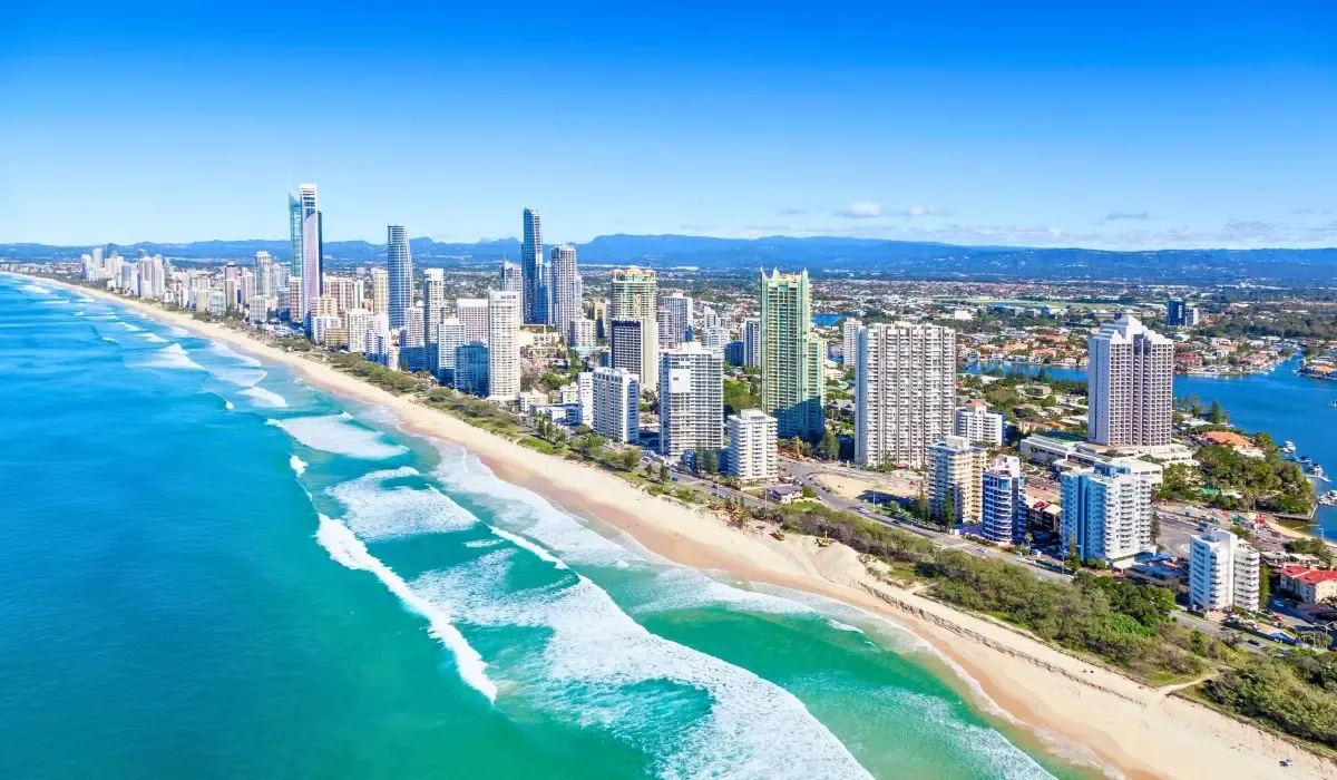 Aerial view of the Gold Coast in Australia featuring modern high-rises, endless beaches, and turquoise ocean waves. Canadians purchasing real estate in Australia can secure favorable CAD to AUD rates and cost-effective money transfers with MTFX.