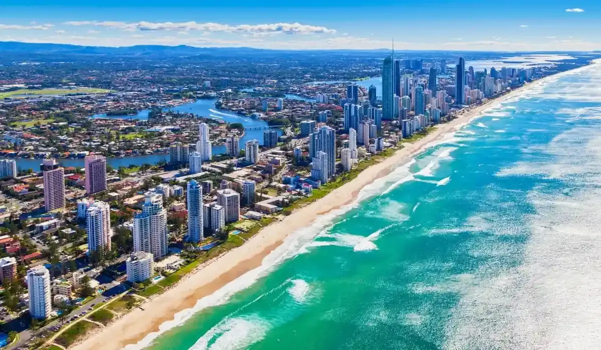 Aerial view of the Gold Coast with high-rise buildings, winding canals, and a long stretch of sandy beach.