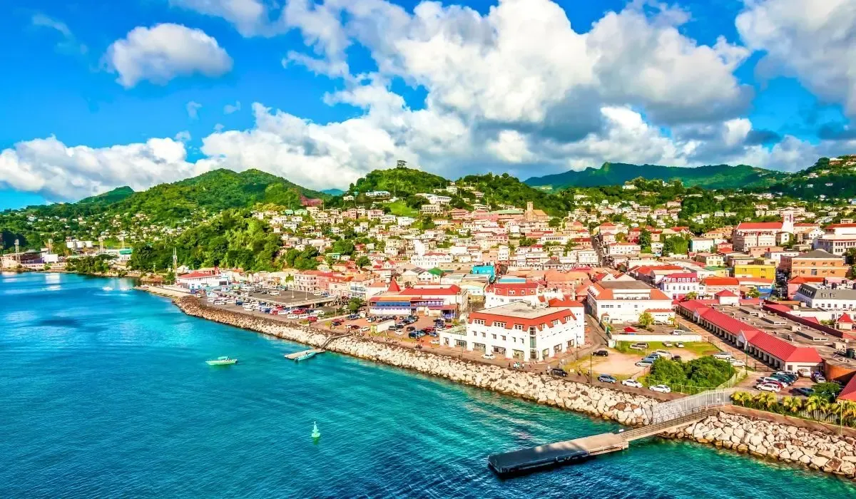 Aerial view of vibrant St. George’s in Grenada, featuring colorful waterfront buildings, lush green hills, and turquoise waters. Canadians exploring Grenada’s real estate can secure low-fee CAD to USD transfers for property payments with MTFX.