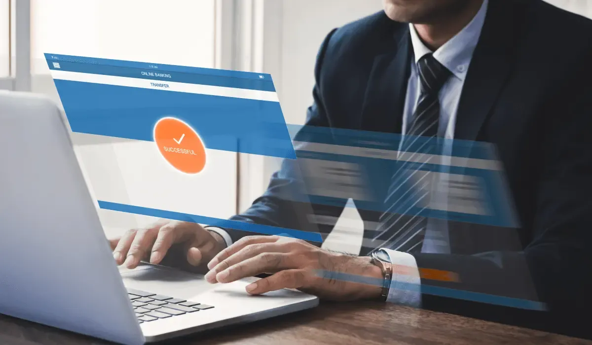 Businessman in a suit using a laptop with a digital overlay showing a successful online money transfer.