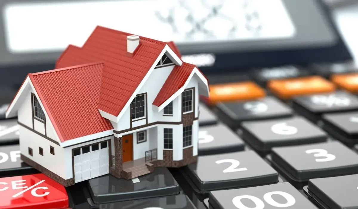 A miniature house model with a red roof placed on a calculator, symbolizing mortgage payments and financial planning.