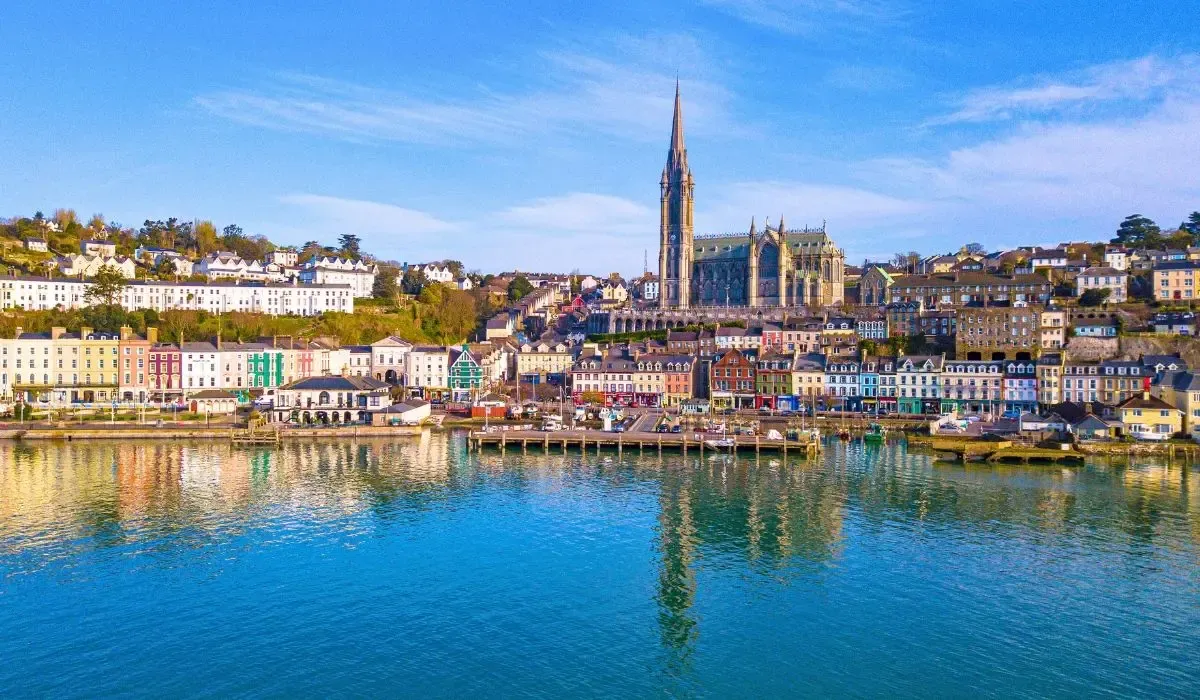 A scenic view of Dublin, Ireland, featuring the River Liffey, historic buildings, and the Ha'penny Bridge under a partly cloudy sky.