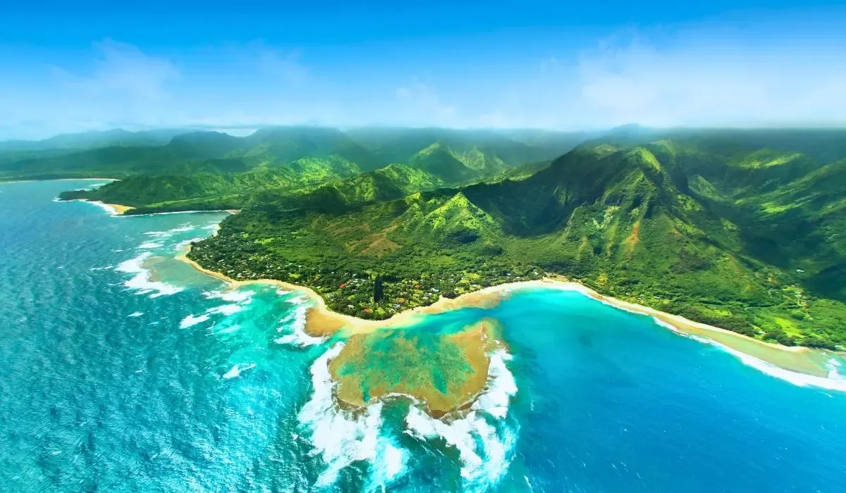 Aerial view of Kauai’s lush mountains and dramatic coastline, where turquoise waters meet sandy shores. Canadians buying property in Hawaii can secure favorable CAD to USD exchange rates and save on large transfers with MTFX.