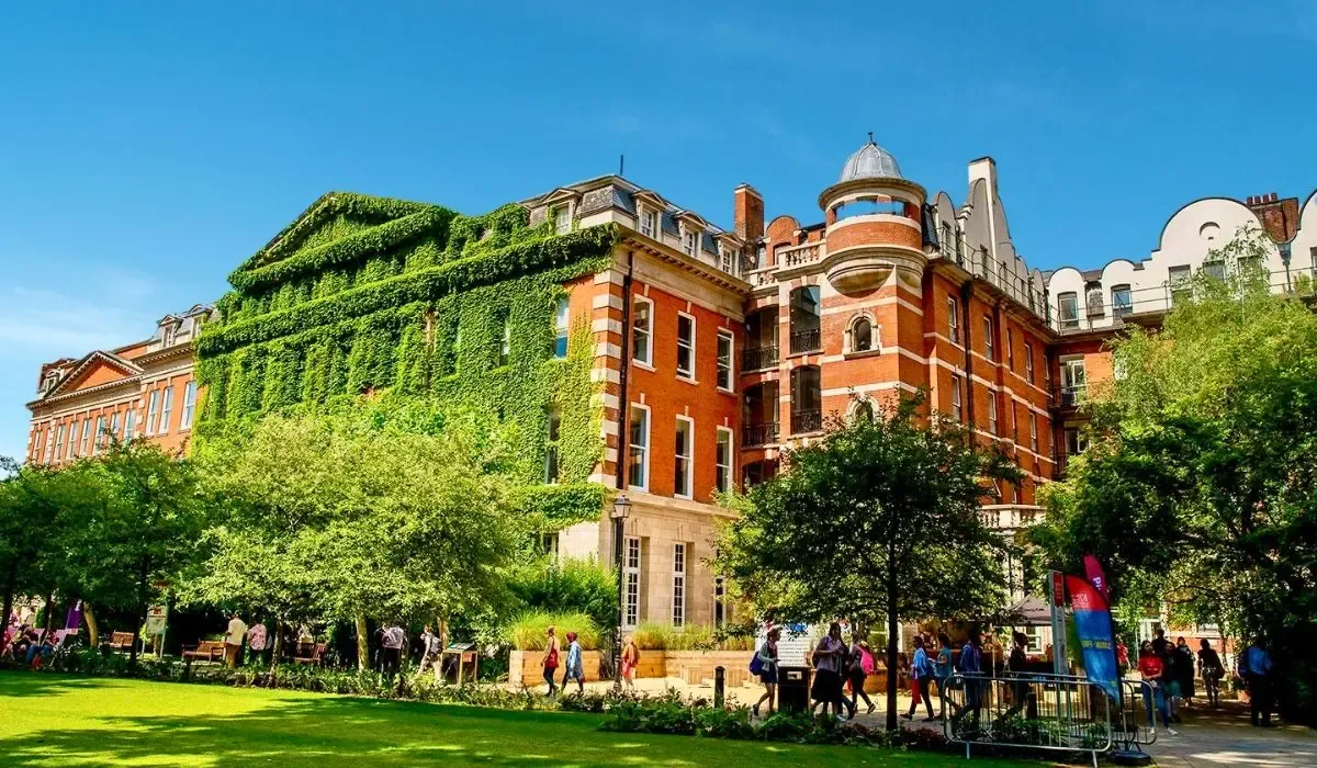 Red-brick and ivy-covered buildings at King’s College London with students walking through a lively courtyard.
