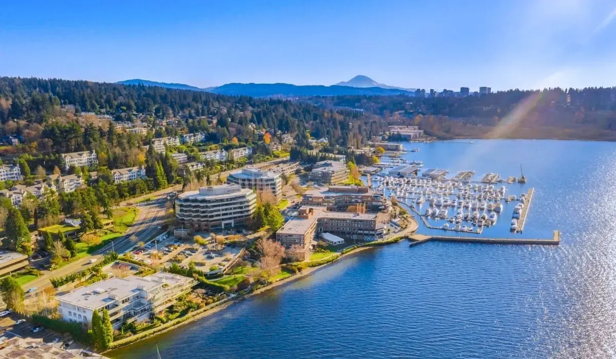A picturesque scene of Kirkland's waterfront area with sailboats docked at the marina, adjacent to a park with walking trails and residential buildings.