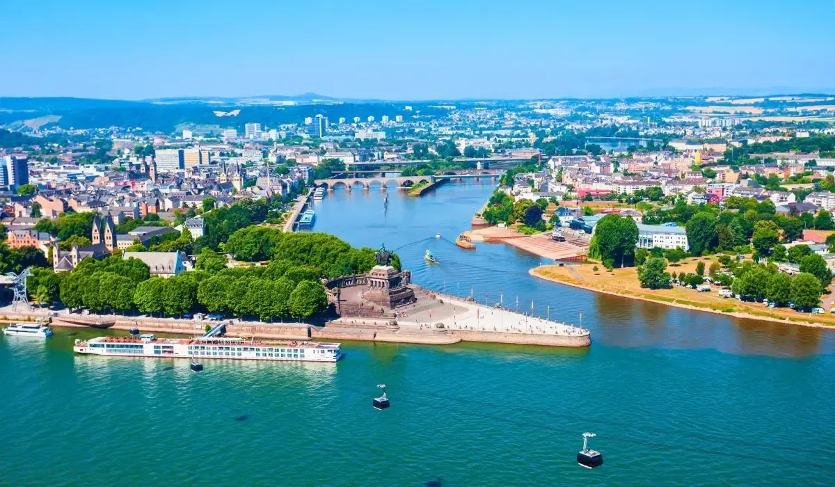 Aerial view of Koblenz, Germany, where the Rhine and Moselle rivers meet at Deutsches Eck monument, surrounded by city architecture and green landscapes. Canadians buying property in Germany can secure great CAD to EUR rates and low transfer costs through MTFX.