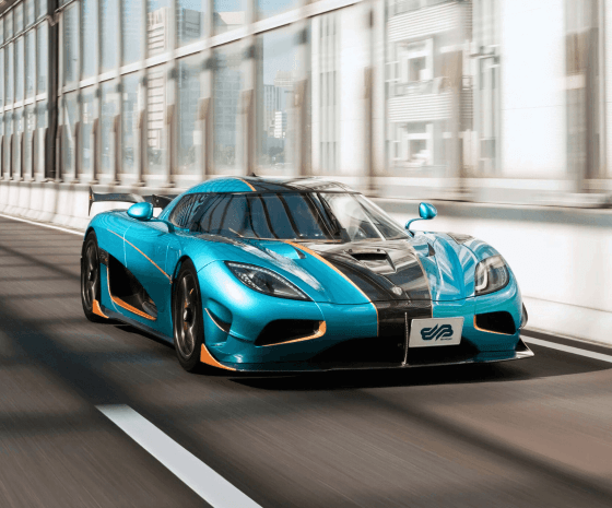 Blue hypercar with orange accents driving on a modern city bridge in daylight