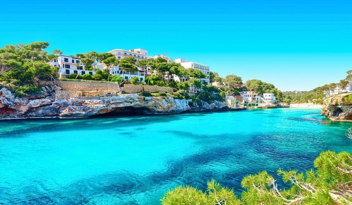 Seaside view of Mallorca, Spain featuring turquoise waters, rocky cliffs, and Mediterranean homes.