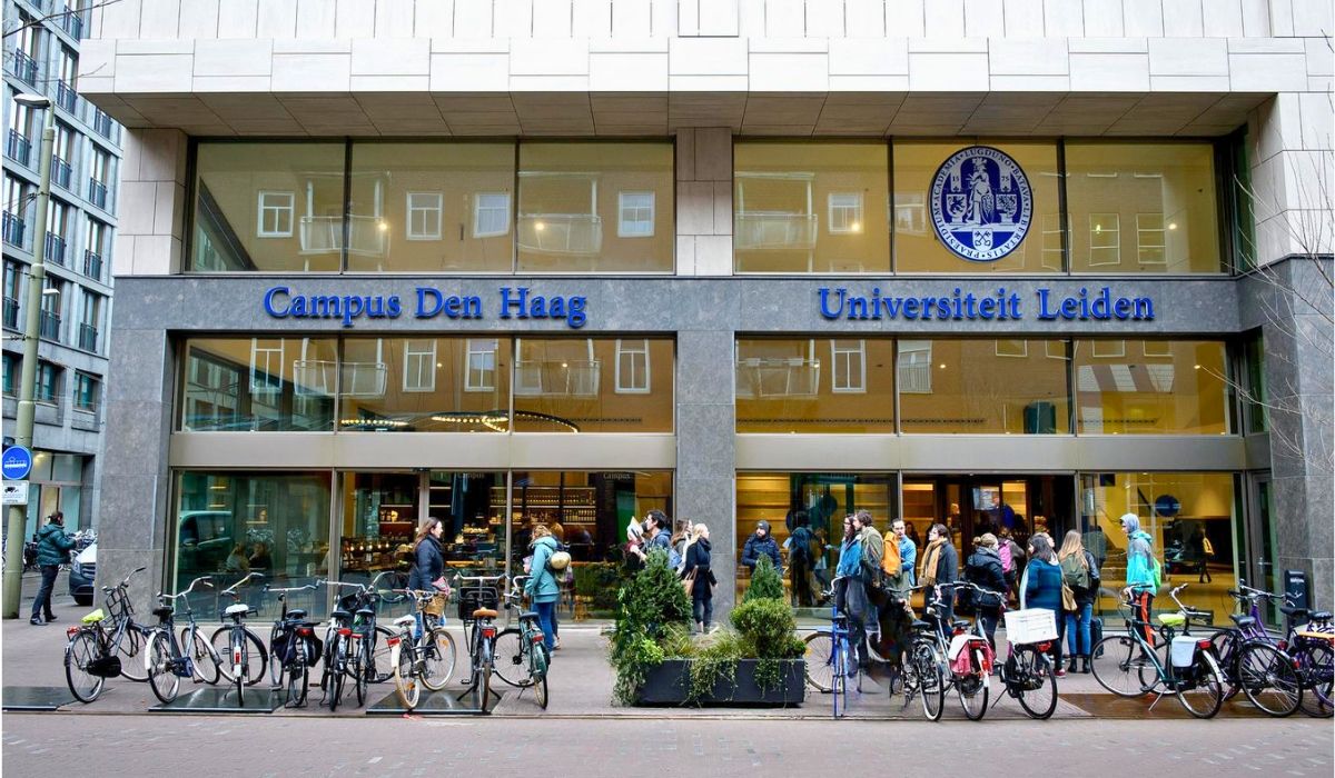 An image of Leiden University's main building, showcasing its classical architecture with students walking and conversing.