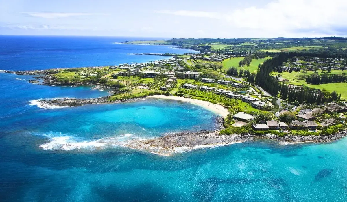Scenic aerial of Maui, Hawaii’s coastline, with clear blue water, rocky shores, and resort properties nestled amid greenery. Canadians investing in property in Hawaii can lock in competitive CAD to USD rates and reduce transfer fees via MTFX.