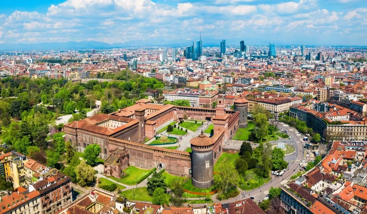 Aerial view of Milan, Italy showcasing the historic Sforza Castle surrounded by lush greenery and the modern city skyline beyond. Canadians interested in buying property in Italy can benefit from favorable CAD to EUR rates and secure transfers with MTFX.